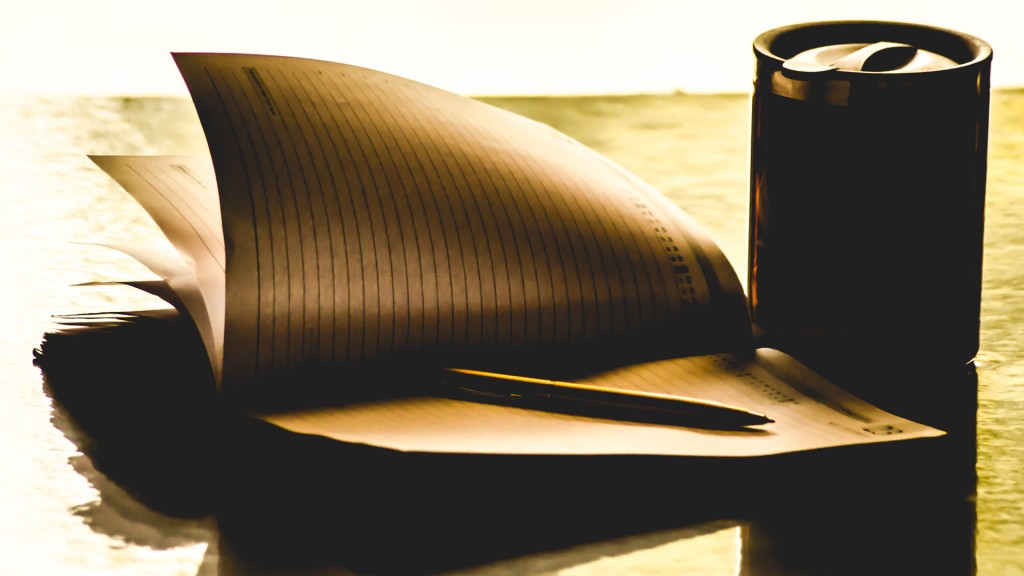 A pen kept on a diary with swirling pages with a coffee mug beside it.