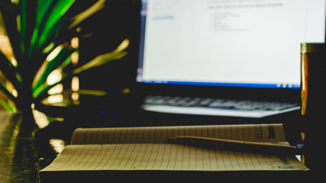 A pen,a diary,a coffee mug and a laptop in the frame.